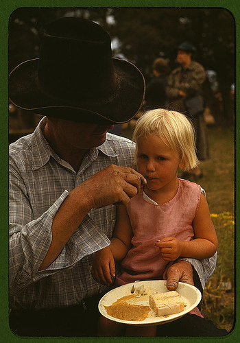 Un padre offre un pezzo di torta alla figlia piccola